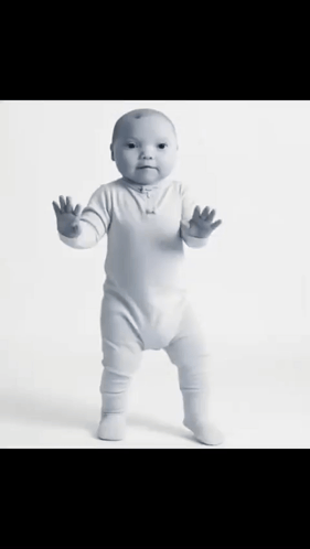 A Baby In A White Bodysuit Is Standing On Its Hind Legs GIF