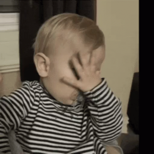 A Baby Is Covering His Face With His Hand . GIF