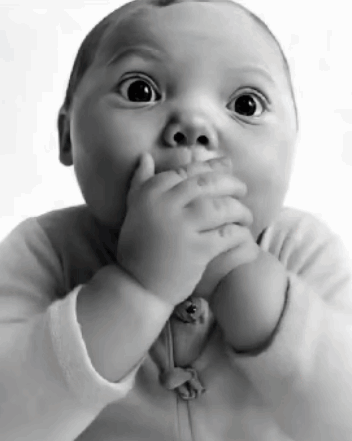 a baby is covering his mouth with his hands