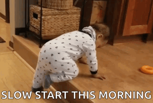 A Baby Is Crawling On A Wooden Floor With The Words Slow Start This Morning Written Below It GIF