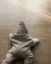 A Baby Is Crawling On The Floor In A Star Shaped Outfit . GIF
