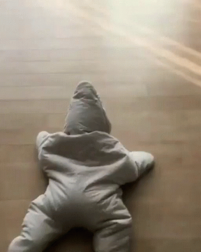 A Baby Is Crawling On The Floor Wearing A Star Shaped Outfit . GIF