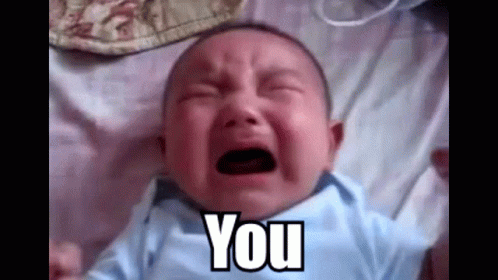 A Baby Is Crying While Laying On A Bed And The Baby Is Saying `` You '' . GIF
