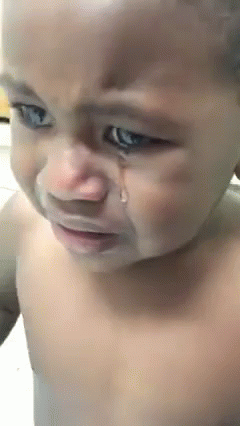 A Baby Is Crying With A Tear Coming Out Of His Eye . GIF
