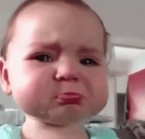 A Baby Is Crying With Tears Coming Out Of His Eyes And A Pacifier In His Mouth . GIF