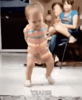 A Baby Is Dancing On The Floor In A Living Room While A Woman Holds Her . GIF
