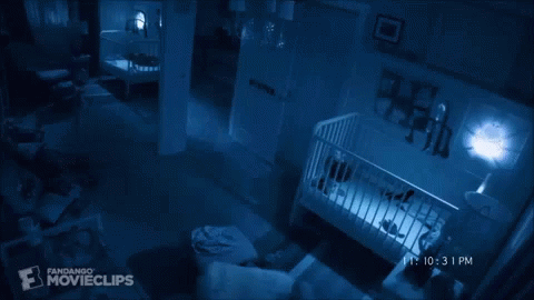 A Baby Is Laying In A Crib In A Dark Room With A Fandango Movieclips Logo In The Corner GIF