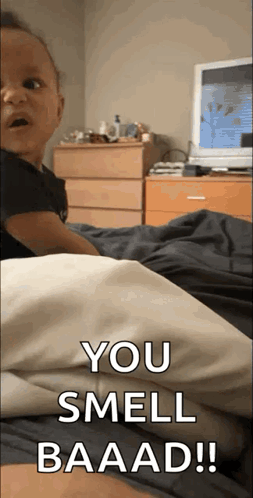 A Baby Is Laying On A Bed With The Words You Smell Baaad Written On The Bottom GIF