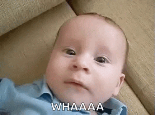 A Baby Is Laying On A Couch And Making A Funny Face While Looking At The Camera . GIF
