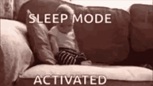 A Baby Is Laying On A Couch With The Words `` Sleep Mode Activated '' Above It . GIF
