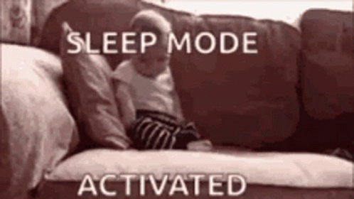 A Baby Is Laying On A Couch With The Words `` Sleep Mode Activated '' Written Above It . GIF