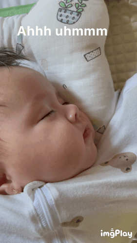 a baby is laying on a pillow with the words ahhh uhmmm written on it