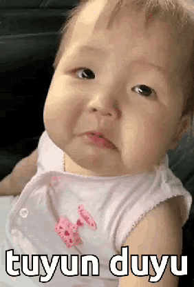 A Baby Is Making A Funny Face And The Baby Is Wearing A White Shirt . GIF
