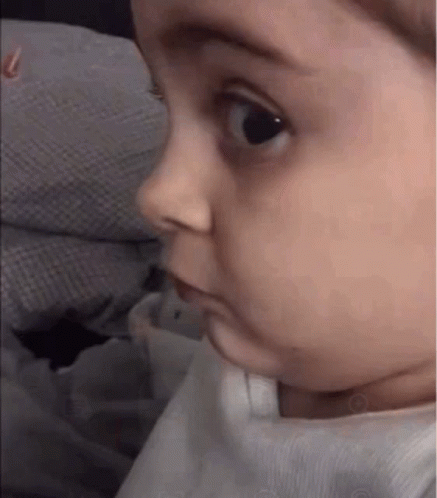 A Baby Is Making A Funny Face While Looking At The Camera . GIF