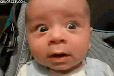 A Baby Is Making A Funny Face With His Mouth Open . GIF
