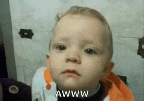 A Baby Is Making A Funny Face With The Words Awww Written Next To Him . GIF