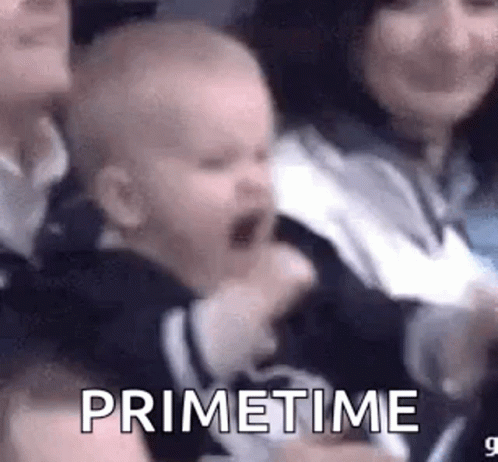 A Baby Is Screaming In A Crowd Of People While Sitting In A Chair . GIF