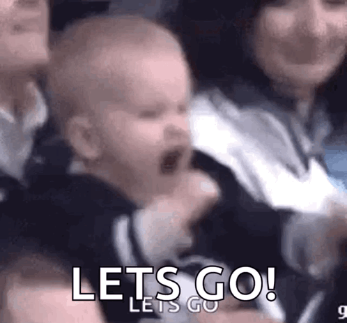 A Baby Is Screaming In A Crowd While A Woman Holds Him . GIF