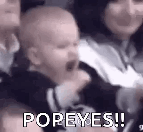 A Baby Is Screaming In A Crowd While Being Held By A Woman And A Man . GIF