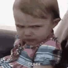 A Baby Is Sitting In A Car Seat With A Funny Face . GIF