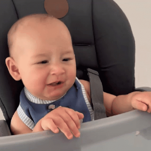 A Baby Is Sitting In A High Chair And Looking At Something GIF
