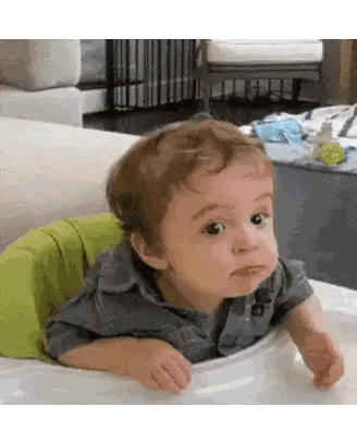 a baby is sitting in a high chair and making a face