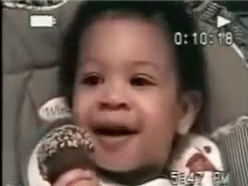 A Baby Is Sitting In A High Chair Eating A Donut . GIF