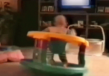 A Baby Is Sitting In A Rocking Chair In Front Of A Tv GIF