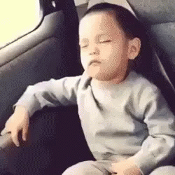 A Baby Is Sitting In The Back Seat Of A Car With His Eyes Closed . GIF