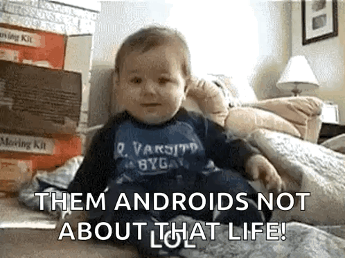 A Baby Is Sitting On A Bed With The Words " Them Androids Not About That Life " On The Bottom GIF