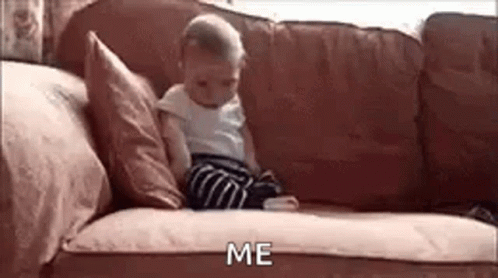 a baby is sitting on a couch looking at a cell phone and saying `` me '' .