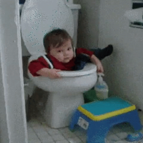 A Baby Is Sitting On A Toilet With A Blue Stool Next To It GIF