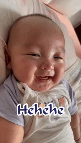 A Baby Is Smiling And Has The Word Henehe Written On His Shirt GIF