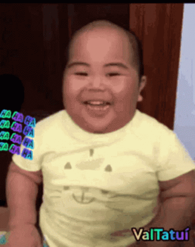 A Baby Is Smiling And Wearing A Yellow Shirt With A Cat Face On It GIF