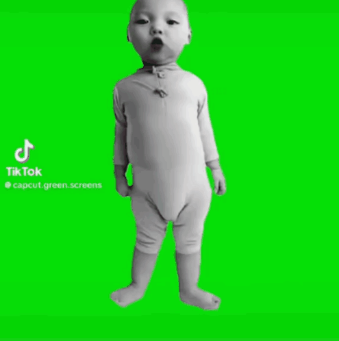 A Baby Is Standing In Front Of A Green Screen . GIF