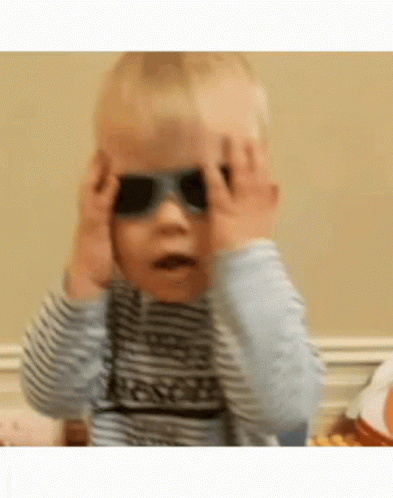 a baby is wearing sunglasses and covering his eyes .