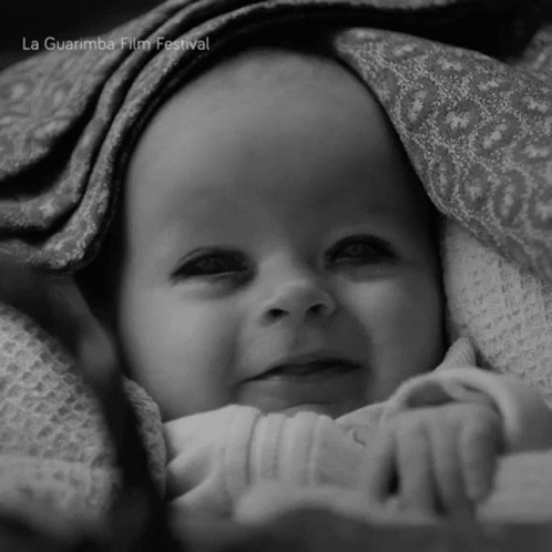 A Baby Is Wrapped In A Blanket With La Guarimba Film Festival Written On The Bottom Right GIF