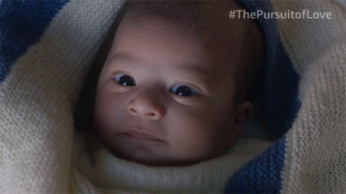 a baby is wrapped in a blue and white striped blanket with #thepursuitoflove written on the bottom