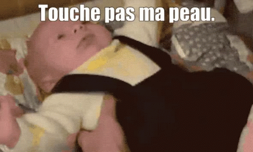 A Baby Laying On A Bed With The Words " Touche Pas Ma Peau " Written Above It GIF