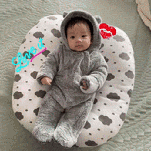 a baby wearing a bear costume is laying on a pillow with a kiss on it