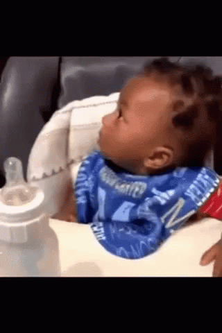 A Baby Wearing A Bib That Says Water On It Is Sitting In A High Chair GIF