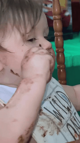 A Baby Wearing A Bib With Wild On It GIF