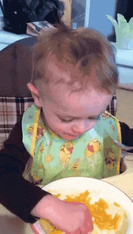 A Baby Wearing A Bib With Winnie Pooh On It GIF