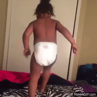 A Baby Wearing A Diaper Is Dancing On A Bed . GIF