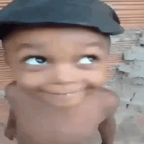 A Baby Wearing A Hat Is Smiling And Looking Up . GIF