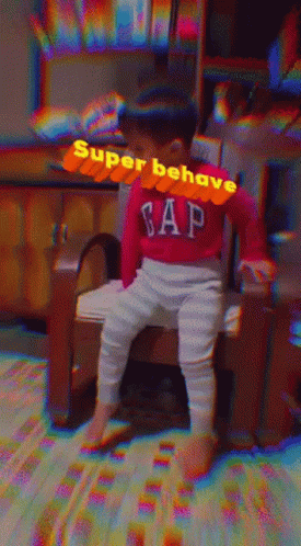A Baby Wearing A Red Gap Sweater Sits On A Chair GIF
