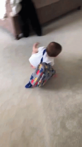 A Baby With A Backpack Is Crawling On The Floor . GIF