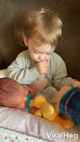 a baby with a pacifier in his mouth is being held by a young boy .