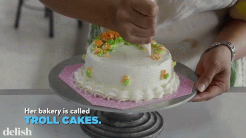 A Bakery Is Called Troll Cakes With A Cake On A Stand GIF