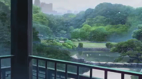 A Balcony With A View Of A Park With Trees And A Pond GIF